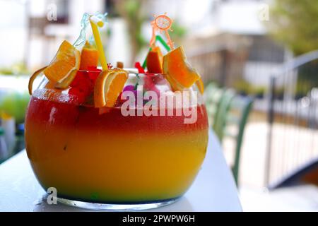 Großes kugelförmiges Glas für Kokzidiosen im Freien auf dem Bartisch im Sommer. Bokeh mit Stühlen im Hintergrund. Stockfoto