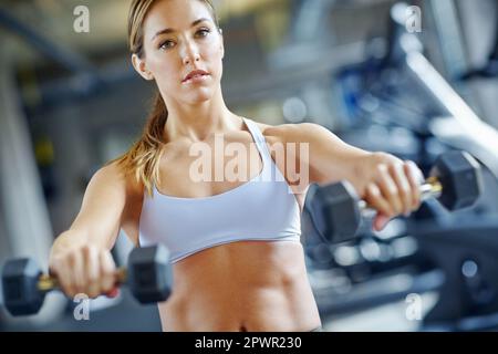 Ich mache große Fortschritte. Eine wunderschöne junge Frau, die im Fitnessstudio trainiert. Stockfoto