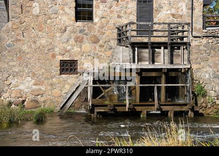 Das Rad der Wassermühle dreht sich unter einem Wasserstrahl. Stockfoto