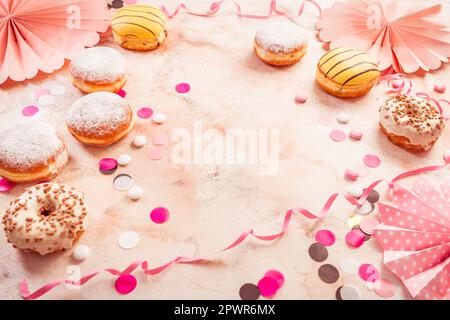 Traditioneller Berliner für Fasching und Party. Deutsch Krapfen oder Donuts mit Streamer und Konfetti. Bunte Karneval oder Geburtstag Bild Stockfoto