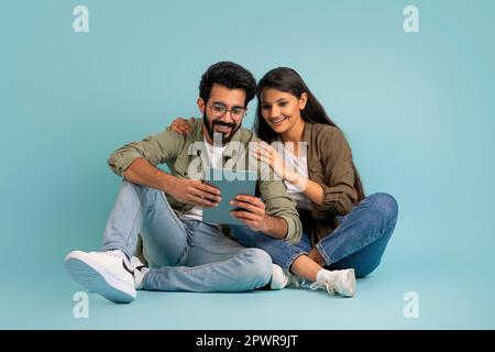 Liebendes junges indisches Paar, das zusammen ein digitales Tablet benutzt Stockfoto
