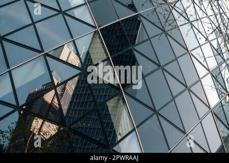 Nahaufnahme des Gherkin-Gebäudes in der Stadt london. Die Glasscheiben erscheinen gekrümmt, sind es aber nicht. Gebäude werden reflektiert. Stockfoto