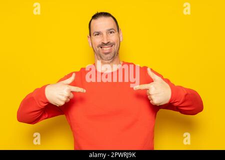 Bärtiger hispanischer Mann in seinen 40s Jahren, der einen roten Pullover trug, selbstbewusst aussah, mit einem Lächeln im Gesicht, der mit dem Finger auf sich selbst zeigte, stolz und glücklich. Isoliert Stockfoto