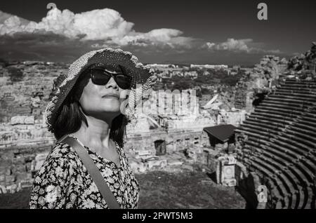 Eine vietnamesische Asiatin mit Hut und Sonnenbrille besucht das große und gut erhaltene römische Amphitheater in Side in der Provinz Antalya, Tur Stockfoto