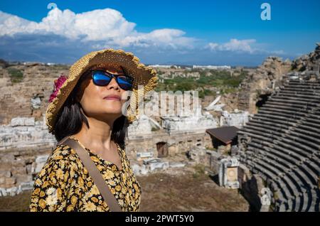 Eine vietnamesische Asiatin mit Hut und Sonnenbrille besucht das große und gut erhaltene römische Amphitheater in Side in der Provinz Antalya, Tur Stockfoto