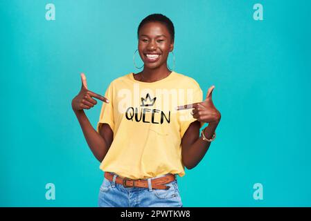 Der Name sagt alles. Studioaufnahme einer selbstbewussten jungen Frau, die ein T-Shirt mit Queen-Shirt auf türkisfarbenem Hintergrund trägt Stockfoto