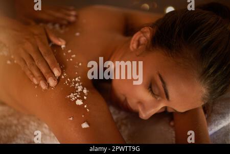 Jeder Tag sollte ein Wellness-Tag sein. Eine junge Frau, die eine Salz-Peeling-Behandlung in einem Spa genießt. Stockfoto