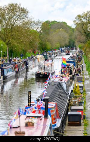 Ein Narrowboat, das zwischen festsitzenden, rotierenden Handelsbooten auf dem Kanal an der Norbury Junction in Staffordshire vorbeifährt. Stockfoto