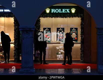 UDINE, Italien - 8. Dezember 2022: Menschen vor den Schaufenstern des Rolex Store in der Mercatovecchio Straße dekoriert in einem Weihnachtsthema Stockfoto
