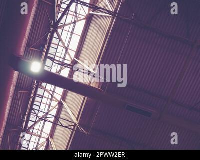 Das Dach eines Hangars, einer Produktionshalle oder einer Sporthalle. Metallkonstruktionen, Balken, Stützelemente. Lüftungsanlagen in großen Hallen und Räumen. Stockfoto