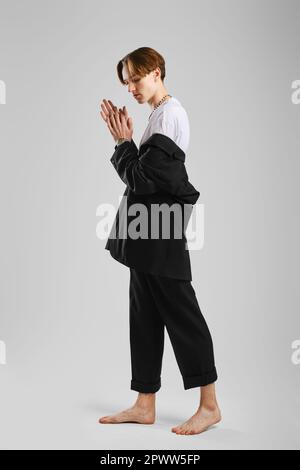 Junger Barfußmann in schwarzem Anzug posiert im Studio Stockfoto