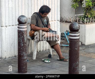 BANGKOK, THAILAND, FEBRUAR 04 2023, Ein Mann repariert einen Schuh im Stadtzentrum auf dem Bürgersteig Stockfoto