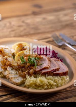 Geräuchertes Fleisch, serviert mit Rot- und Weißkohl und zwei Sorten Knödel Stockfoto