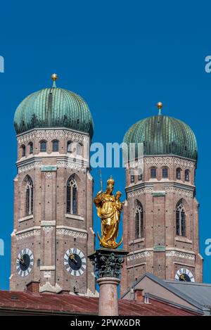 Die goldene Statue der Mariensäule auf dem Marienplatz in der Münchner Altstadt, eingerahmt von den beiden Türmen der Frauenkirche bei sonnigem Wetter und Stockfoto