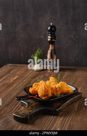 Scharfe, frittierte panierte Hähnchenflügel auf schäbigem Servierbrett Stockfoto