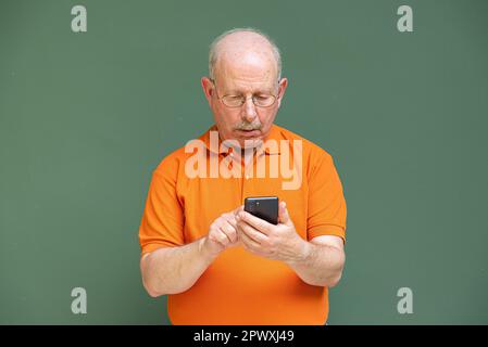 Porträt eines grauhaarigen Seniorenmannes mit Schnurrbart, Brille und Handy Stockfoto