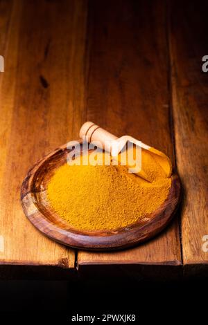 Kurkumapulver in einem Holzlöffel und einer Schüssel Stockfoto