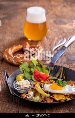 österreichisches Kartoffelgericht auf Holz mit Bier Stockfoto