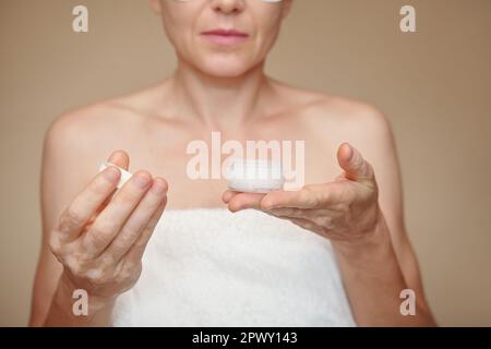 Reife Frau, die ein kleines Glas mit organischem Gesichtspeeling öffnet Stockfoto