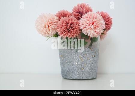 Strauß aus rosafarbenen künstlichen Frottblumen in einer grauen silbernen Vase auf weißem Hintergrund. Stillleben, Dekoration möglich. Zimmereinrichtung. Freier Platz f Stockfoto