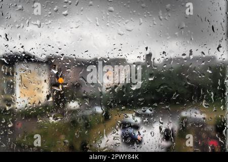 Schlechtes Wetter in der Stadt. Gebäude, Häuser, Autos vor dem Fenster. Wolkenbewölkung. Meteorologie und Wettervorhersage. Heruntergekommene Regentropfen Stockfoto