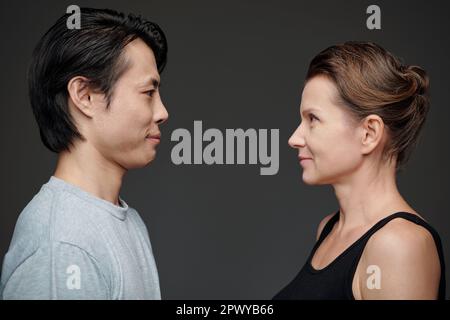 Mann und Frau stehen vor grauem Hintergrund und sehen sich an Stockfoto