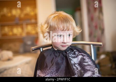 Das glückliche kleine Mädchen zeigt sich im Schönheitssalon. Stockfoto