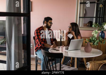 Ernsthafte Ehefrau und Ehemann planen Budget, prüfen Finanzen, fokussierte junge Frau mit Online-Rechner und Zählen von Rechnungen oder Steuern, Mann mit Laptop Stockfoto