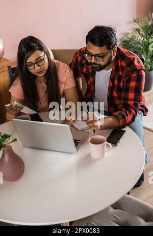 Ernsthafte Ehefrau und Ehemann planen Budget, prüfen Finanzen, fokussierte junge Frau mit Online-Rechner und Zählen von Rechnungen oder Steuern, Mann mit Laptop Stockfoto