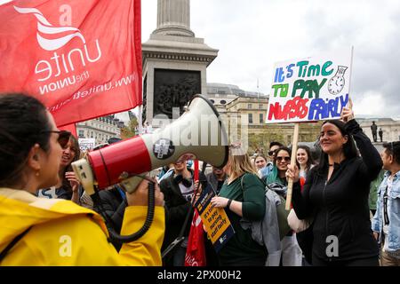 London, Großbritannien. 01. Mai 2023. Eine Krankenschwester spricht über ein Megaphon mit anderen Demonstranten, während eine andere auf einem Plakat „Zeit, Krankenschwestern fair zu bezahlen“ während einer Kundgebung der Krankenschwestern am Trafalgar Square anlässlich des Maifeiertags hält. Krankenschwestern marschieren vom St. Thomas' Hospital zum Trafalgar Square im Zentrum von London am Mai Streik für 24 Stunden über Bezahlung, Rekrutierung und Verbleib im nationalen Gesundheitsdienst. Kredit: SOPA Images Limited/Alamy Live News Stockfoto