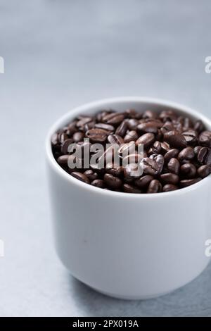 Eine Nahaufnahme einer weißen Tasse voller Kaffeebohnen. Stockfoto