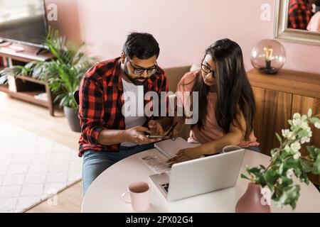 Ernsthafte Ehefrau und Ehemann planen Budget, prüfen Finanzen, fokussierte junge Frau mit Online-Rechner und Zählen von Rechnungen oder Steuern, Mann mit Laptop Stockfoto