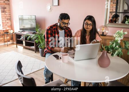 Ernsthafte Ehefrau und Ehemann planen Budget, prüfen Finanzen, fokussierte junge Frau mit Online-Rechner und Zählen von Rechnungen oder Steuern, Mann mit Laptop Stockfoto