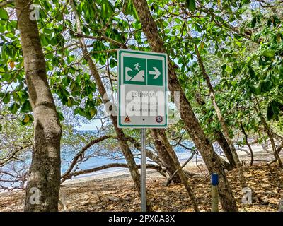 Nationalpark Manuel Antonio, Costa Rica - Ein Schild am Strand des Pazifiks markiert einen Evakuierungsweg im Falle eines Tsunami. Stockfoto
