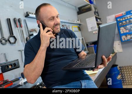 Mittlerer Teil des Mechanikers mit Laptop in der Werkstatt Stockfoto