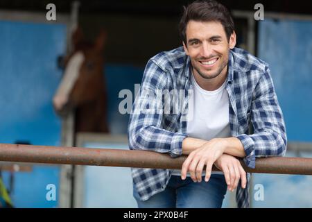 Fröhlicher männlicher Bauer, der im Hangar posiert Stockfoto