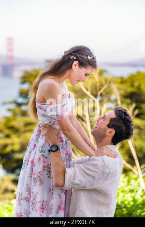 Junges Paar in der Liebe | Golden Gate Bridge im Hintergrund | Mann ergreifende schöne Frau Stockfoto