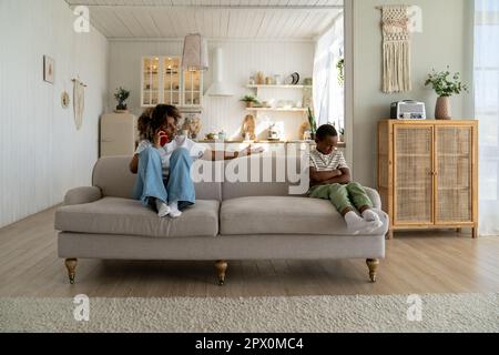 Verärgerte, unglückliche afroamerikanische Mutter, die sich am Telefon über das Verhalten ihres Sohnes beschwerte Stockfoto