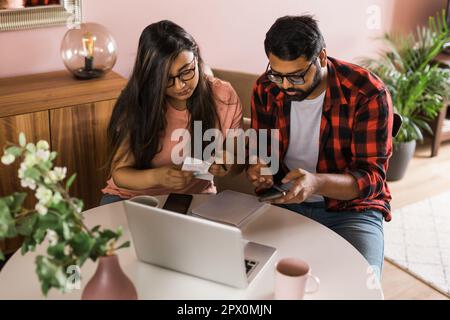 Ernsthafte Ehefrau und Ehemann planen Budget, prüfen Finanzen, fokussierte junge Frau mit Online-Rechner und Zählen von Rechnungen oder Steuern, Mann mit Laptop Stockfoto