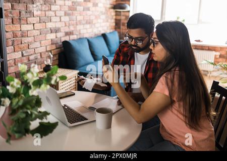 Ernsthafte Ehefrau und Ehemann planen Budget, prüfen Finanzen, fokussierte junge Frau mit Online-Rechner und Zählen von Rechnungen oder Steuern, Mann mit Laptop Stockfoto