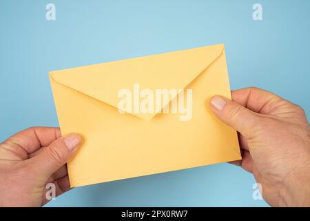 Ein gelber Umschlag in den Händen eines Mannes Stockfoto