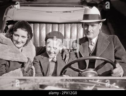 1930S LÄCHELNDER FAMILIENVATER, MUTTER, SOHN, DIE ZUSAMMEN AUF DEM BEIFAHRERSITZ EINES CABRIOLETS MIT TOURING-AUTO VOR DER KAMERA SITZT – M3735 HAR001 HARS DAD REITEN MUTTER HAT NOSTALGISCHE PAAR VORSTADTMÜTTER AUSDRUCK KONVERTIBLE ALTE-ZEIT-NOSTALGIE ALTE MODE 1 SITZ JUGENDLICHER GESICHTSSCHUTZ SÖHNE ZUFRIEDEN FAMILIEN FREUDE LEBENSSTIL FRAUEN VERHEIRATET EHEPARTNER EHEMÄNNER LUXUS KOPIERRAUM HALBE LÄNGE DAMEN PERSONEN MÄNNER TRANSPORT EXPRESSIONS VÄTER AUGENKONTAKT MIT B&W-PARTNERN SUCCESS SUCCESS SUCCESS AND TIE HAPPINESS KOPF UND SCHULTERN FRÖHLICHE VÄTER ERHOLUNGSSTOLZ LÄCHELT SONNTAG DRIVE CONNECTION KONZEPTIONELLE FLUCHT FREUDIG Stockfoto