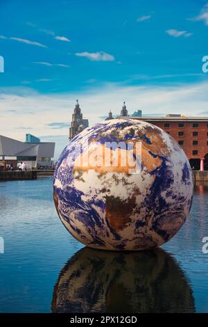 Liverpool, Großbritannien. 29. April 2023. Eine riesige Kunstinstallation mit einem Durchmesser von 10m mm Floating Earth vom Künstler Luke Jerram im Royal Albert Dock Liverpool mit dem berühmten Liver Building im Hintergrund. Kredit: SOPA Images Limited/Alamy Live News Stockfoto