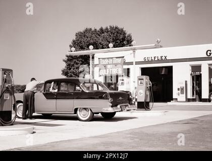 1950S ANONYMER MANN GULF TANKSTELLENWART REINIGT WINDSCHUTZSCHEIBE FÜR FRAU, DIE FÄHRT 1955 VIERTÜRIGE PONTIAC LIMOUSINE - M399 HAR001 HARS GULF LIFESTYLE SATISFACTION WEIBLICHE JOBS KOPIEREN RAUM HALBE LÄNGE DAMEN PERSONEN AUTO MÄNNCHEN TREIBSTOFFTRANSPORT B&W PUMPEN FÄHIGKEITEN BERUF SKILLS TANKSTELLE KUNDENSERVICE LIMOUSINE AUTOS SERVICE STATION BESCHÄFTIGUNG BESCHÄFTIGUNG BESCHÄFTIGUNG BESCHÄFTIGUNG BESCHÄFTIGUNG BENZIN KONZEPT PONTIAC AUTOS FAHRZEUGE WINDSCHUTZSCHEIBE ANGESTELLTER KOOPERATION BENZIN PETROLEUMREIFEN 1955 SCHWARZ-WEISS WEISSE ETHNISCHE HERKUNFT HAR001 ARBEIT ALTMODISCH Stockfoto