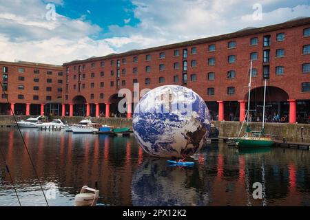 Liverpool, Großbritannien. 29. April 2023. Ein Mann paddelt um die riesige schwimmende Erde mit einem Durchmesser von 10m mm vom Künstler Luke Jerram im Royal Albert Dock Liverpool, das vor dem Eurovision Song Contest angekommen ist. Kredit: SOPA Images Limited/Alamy Live News Stockfoto