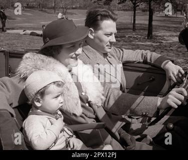 1930S LÄCHELNDE DREIKÖPFIGE FAMILIE AUF DEM VORDERSITZ DES CABRIOLETS VATER FÄHRT MUTTER MIT PELZKRAGEN BABY BOY IN AUTOSITZ - M5460 HAR001 HARS KLEIDUNG NOSTALGISCHES PAAR VORSTADTKRAGEN MÜTTER KONVERTIBEL ALTE ZEIT NOSTALGIE ALTE MODE AUTO 1 SITZPLÄTZE JUGENDFAHRZEUG JUNGER ERWACHSENER SICHERHEIT SÖHNE JOY LIFESTYLE FRAUEN VERHEIRATET EHEPARTNER EHEMÄNNER KOPIEREN WELTRAUMFREUNDSCHAFT HALBE LÄNGE DAMEN PERSONEN AUTO MÄNNER TRANSPORT VÄTER B&W PARTNER FREIHEIT GLÜCK HOCHWINKEL ABENTEUER FREIZEIT AUTOS VÄTER SONNTAGSFAHRT AUTOS ENTFLIEHEN STILVOLL FAHRZEUGE BABY JUNGE KOOPERATION JUGENDLICHE MITTE ERWACHSENER Stockfoto