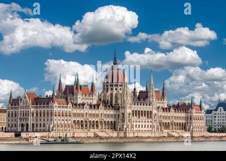 Schräger Blick auf die Außenfassade des ungarischen Parlamentsgebäudes in Budapest an der Donau mit blauem Himmel und Wolken bei schönem Wetter Stockfoto