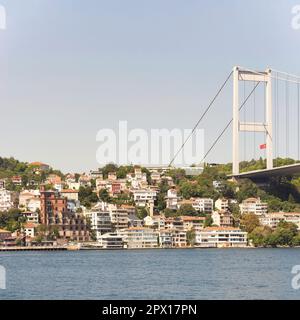 Blick vom Meer auf die europäische Seite der Bosporus-Straße, Istanbul, Türkei, mit traditionellen Häusern am Wasser, unter der Bosporus-Brücke und grünem Hi Stockfoto