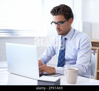 Große Träume erfordern harte Arbeit. Ein gutaussehender Geschäftsmann, der in seinem Büro an einem Laptop arbeitet. Stockfoto