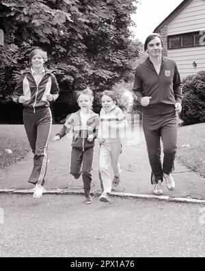 1970S 1980S VORSTADTFAMILIEN MIT MUTTER, VATER, JUNGE, MÄDCHEN, DIE ALLE JOGGINGKLEIDUNG TRAGEN - S21574 HAR001 NOSTALGISCHE, AKTIVE HARS-FAMILIE 4 GEMEINDE VORORT MÜTTER ALTE ZEIT NOSTALGIE BRUDER ALTE MODE SCHWESTER FITNESS JUGENDSTIL GESUNDE JUNGE ERWACHSENE TEAMARBEIT SÖHNE FAMILIEN JOY LIFESTYLE ZUFRIEDENHEIT FRAUEN HÄUSER VERHEIRATETE BRÜDER EHEPARTNER EHEMÄNNER GESUNDHEIT HEIM KOPIEREN WELTRAUM FREUNDSCHAFT VOLLE LÄNGE FRAUEN FITNESS TÖCHTER PERSONEN INSPIRATION WOHNEN MÄNNCHEN GEBÄUDE GESCHWISTER VÄTER B&W PARTNER AUGENKONTAKT ZIELE AKTIVITÄT GLÜCK KÖRPERLICHE WELLNESS FREIZEIT KRAFT VÄTER Stockfoto